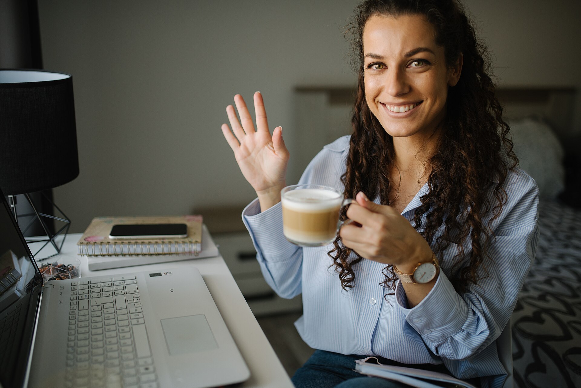 The renewal decision gets made at a desk, in a hurry, with the charge already on the card. Photo: Shixart1985, "Woman enjoying coffee while working on laptop in cozy indoor space during daytime", CC BY 2.0, via Wikimedia Commons.